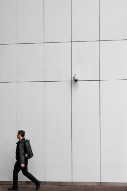 cctv security camera on a wall above a passing person